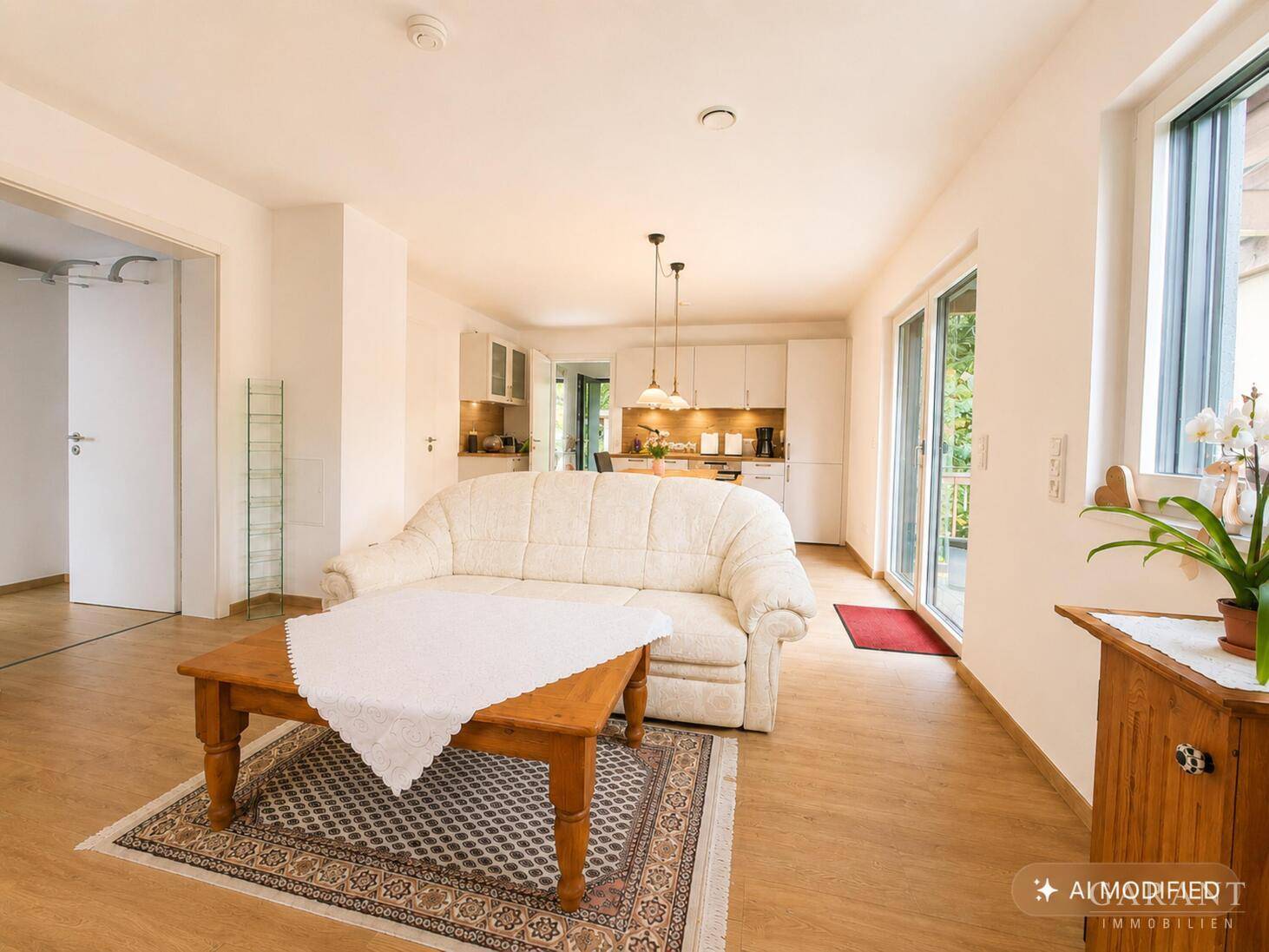 Offener Wohnbereich mit Sofa, Holztisch und Blick in die angrenzende Küche.