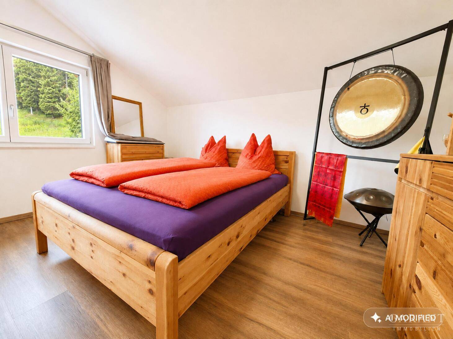 Gemütliches Schlafzimmer mit Holzbett, Holzboden und Fenster mit Blick ins Grüne.