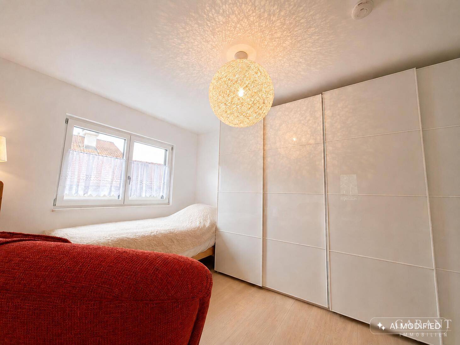 Schlafzimmer mit Einzelbett, weißem Kleiderschrank und Fenster.