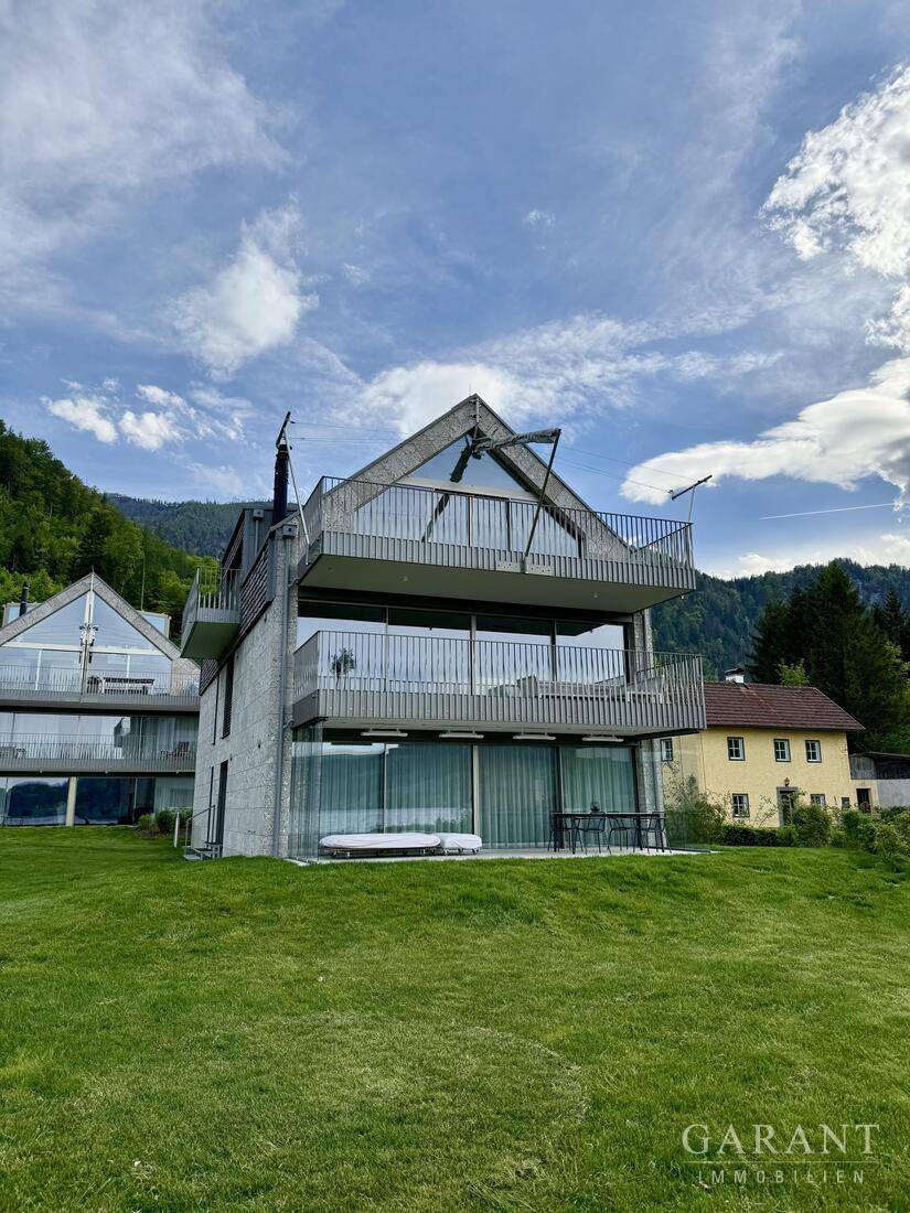 Moderne Architektur des Gebäudes mit mehreren Balkonen und großen Glasflächen am Seeufer, sehr ansprechend.