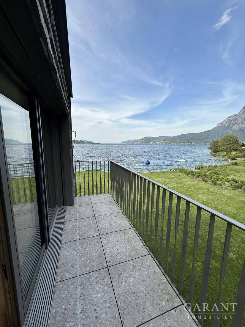 Seitlicher Balkon mit Blick auf das ruhige Wasser des Sees und die grüne Landschaft, ideal für Morgenkaffee.