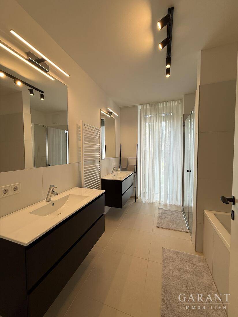 Geräumiges, modernes Badezimmer mit Doppelwaschbecken, Badewanne und separater Dusche.