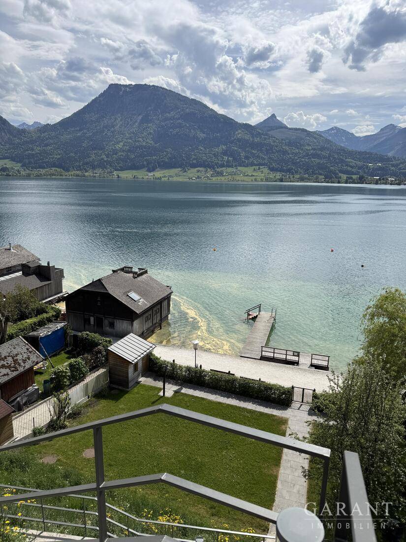 Malerischer Gartenbereich mit direktem Zugang zum See, Bootssteg und beeindruckendem Bergpanorama.