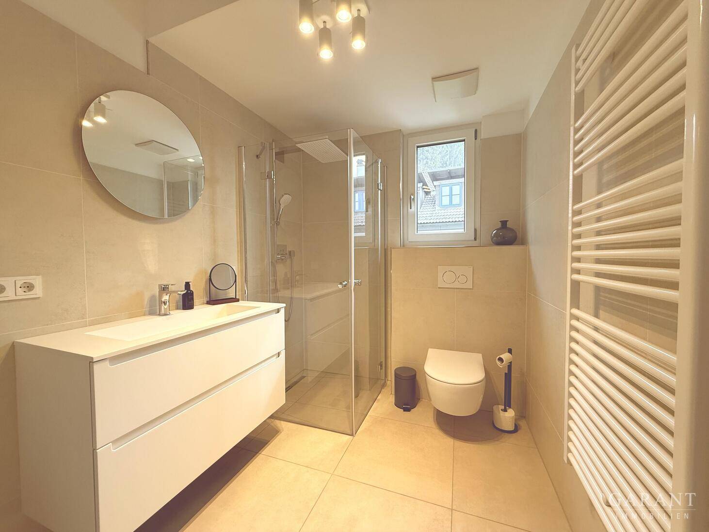 Helles Badezimmer mit begehbarer Dusche, modernem Waschtisch und beheiztem Handtuchhalter.