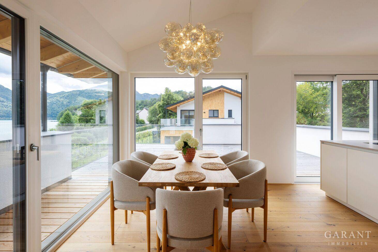 Moderner Essbereich mit Holztisch und Zugang zu einem Balkon mit Blick auf die umliegende Landschaft.