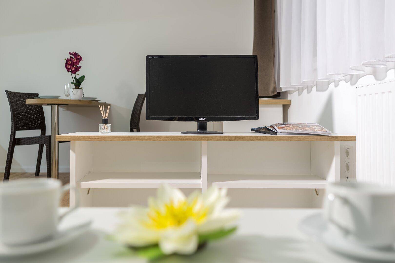 Wohnbereich mit Fernseher und angrenzendem Essbereich, funktional und kompakt.