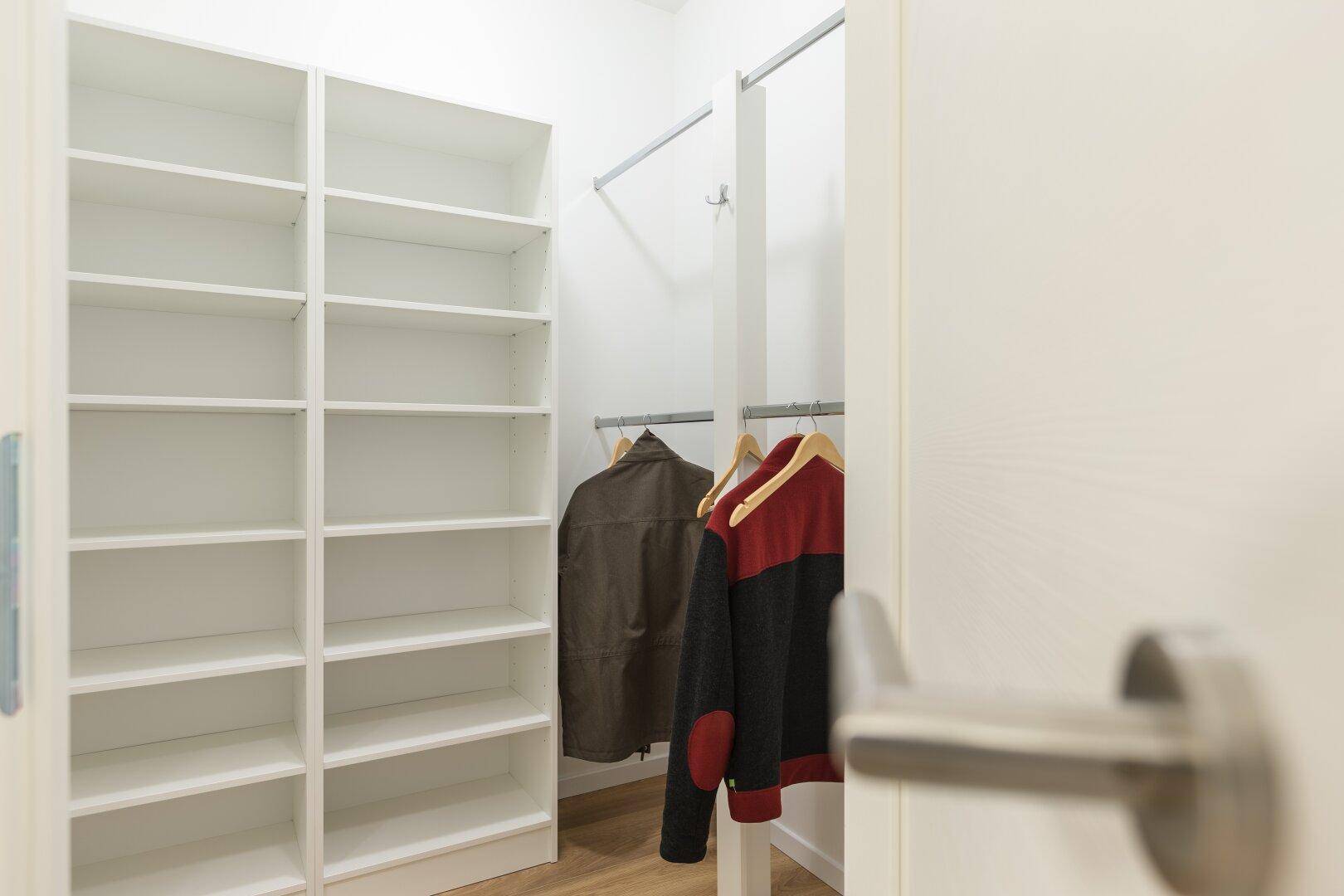 Begehbarer Kleiderschrank mit Kleiderstangen und Regalsystem für optimale Organisation.