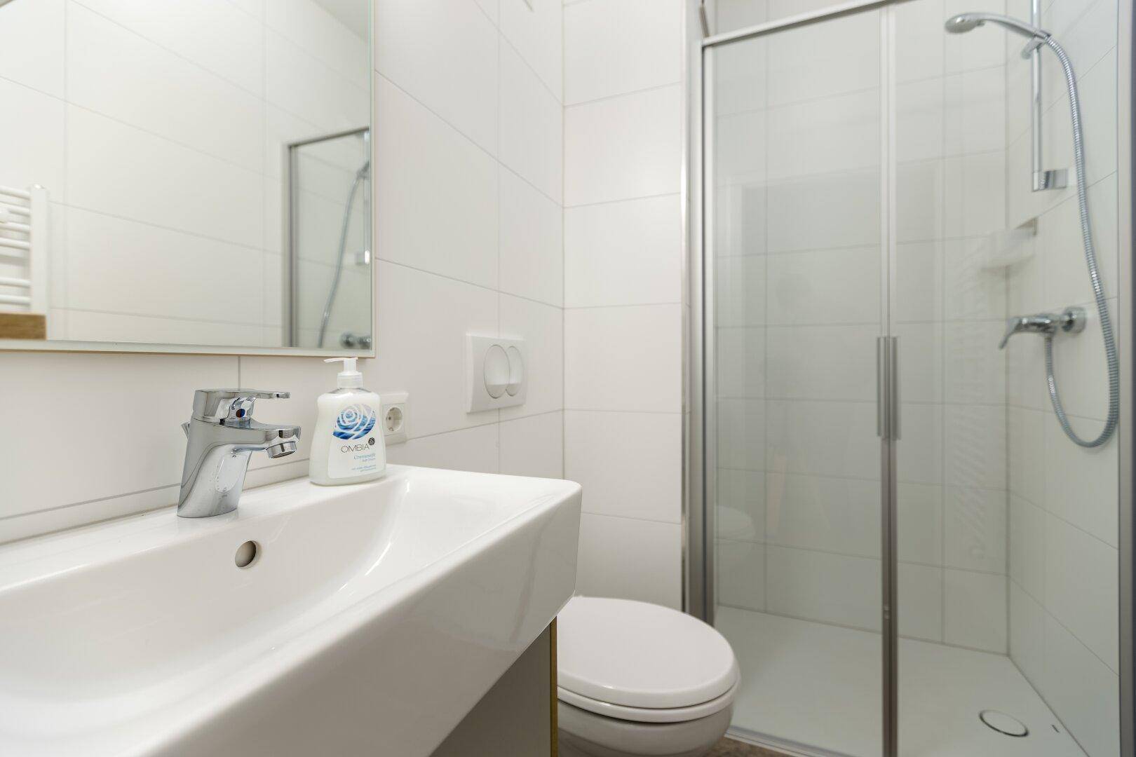 Waschbecken und Toilette in einem hell gefliesten Badezimmer.