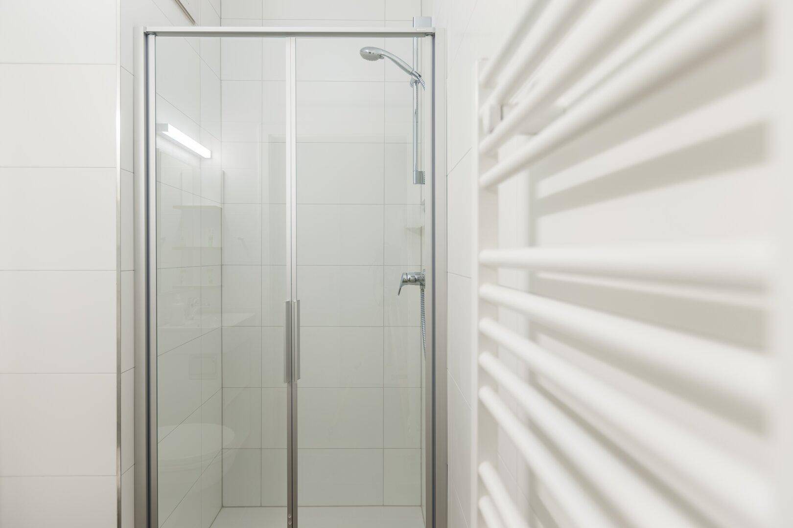 Duschkabine mit Glasabtrennung und beheiztem Handtuchhalter im Badezimmer.