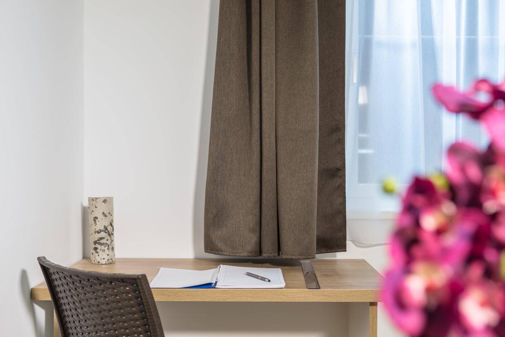 Kleiner Arbeitsbereich mit Schreibtisch und Fenster, ideal für Home-Office.