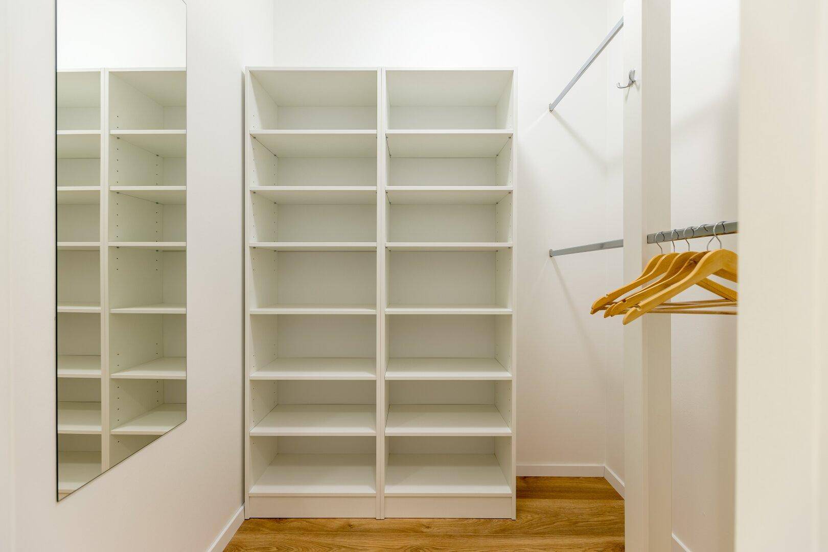 Geräumiger begehbarer Kleiderschrank mit vielen Regalen und einem großen Spiegel.