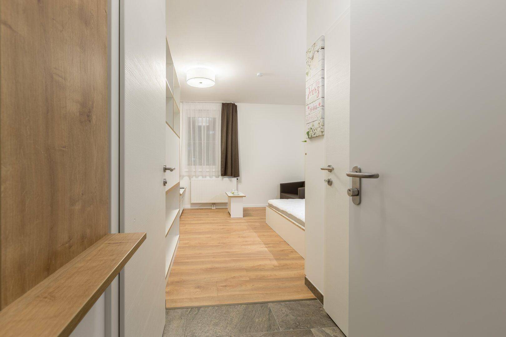 Eingangsbereich eines Studio-Apartments mit Blick in den Wohn- und Schlafbereich.