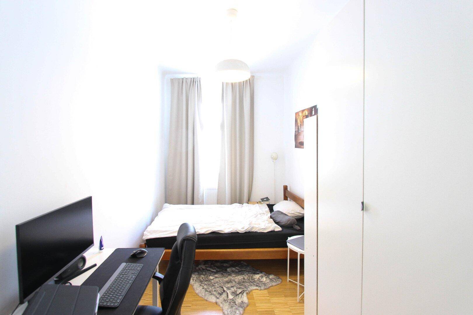 Gemütliches Schlafzimmer mit Bett, Schreibtisch und Fenster, ideal für Studenten oder Singles.