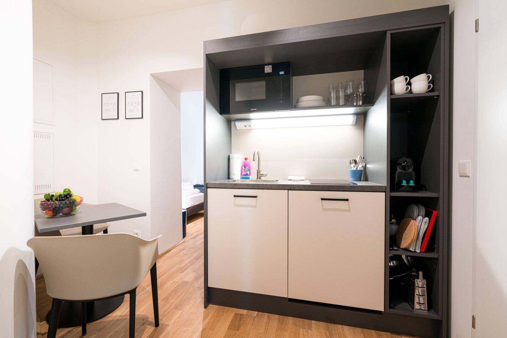 Moderne Küchenzeile mit Mikrowelle und integrierten Schränken, ideal für kleine Wohnungen.