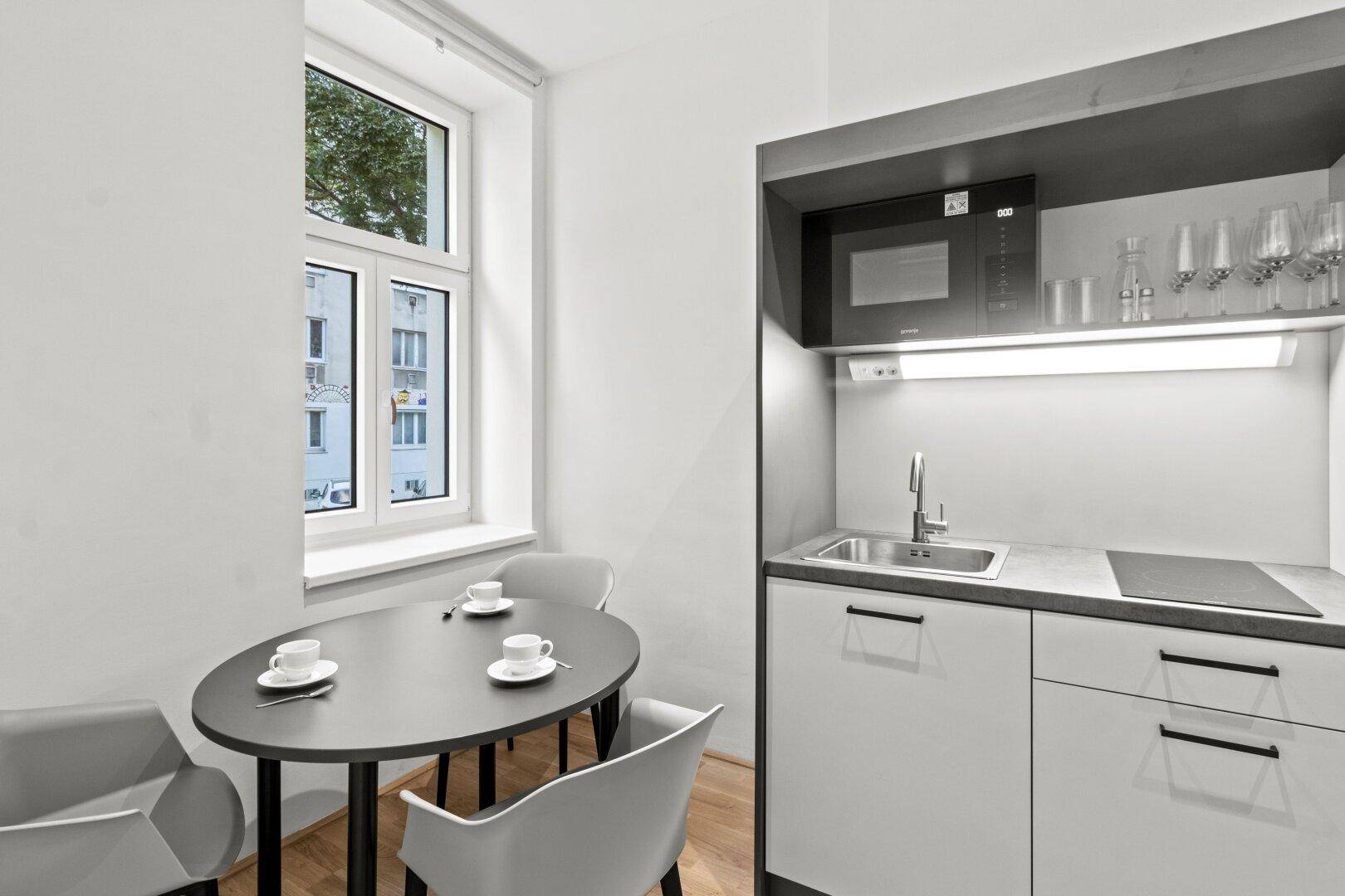 Kleine Küchenzeile mit Essbereich am Fenster, bietet Funktionalität und Tageslicht.