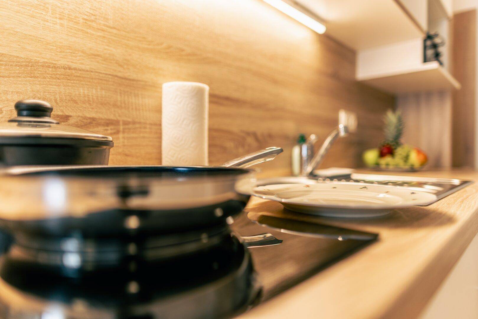 Moderne Küchenzeile mit Induktionskochfeld und Holz-Arbeitsplatte für effizientes Kochen.