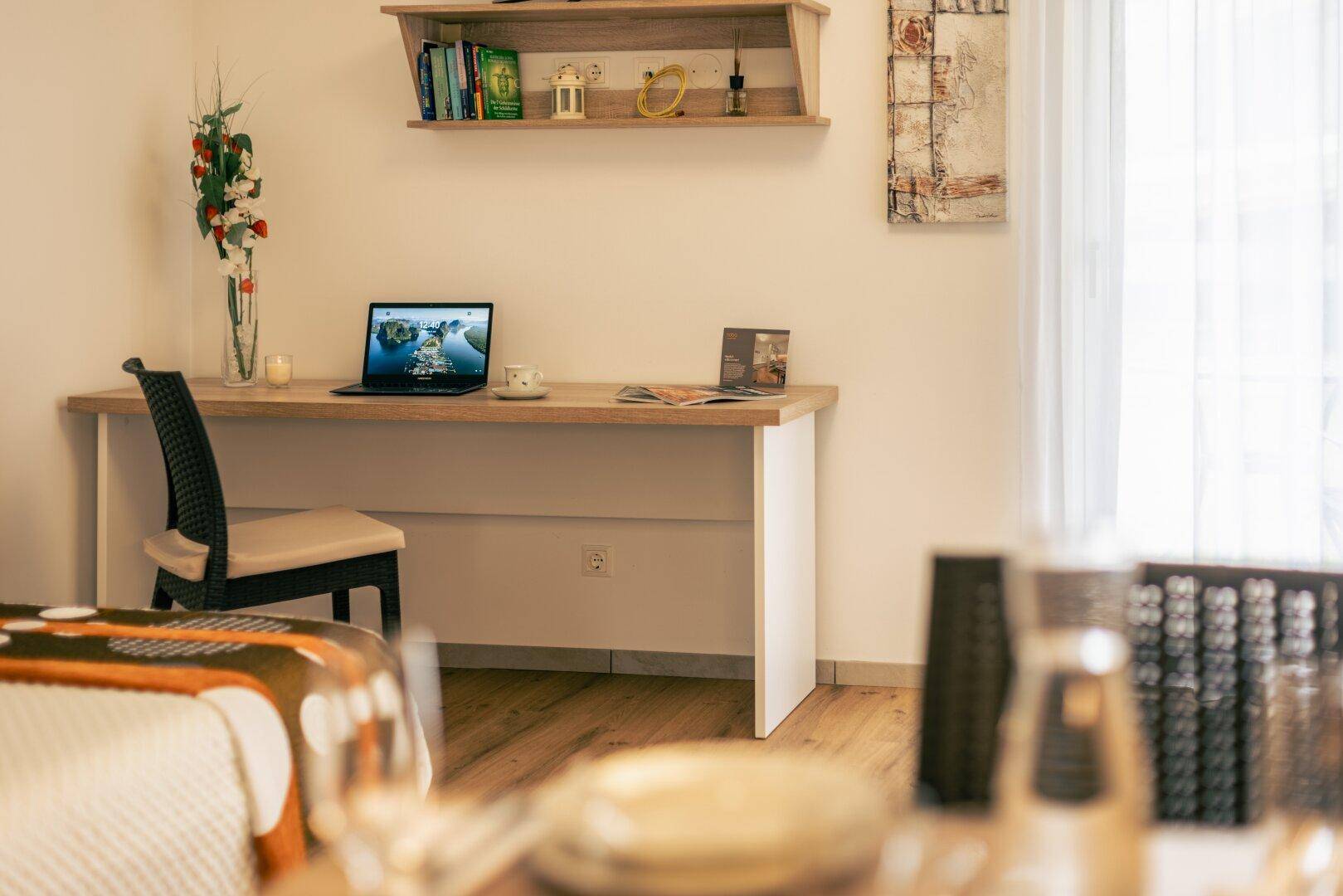 Arbeitsbereich mit Schreibtisch, Laptop und Regal, hell und funktional gestaltet.