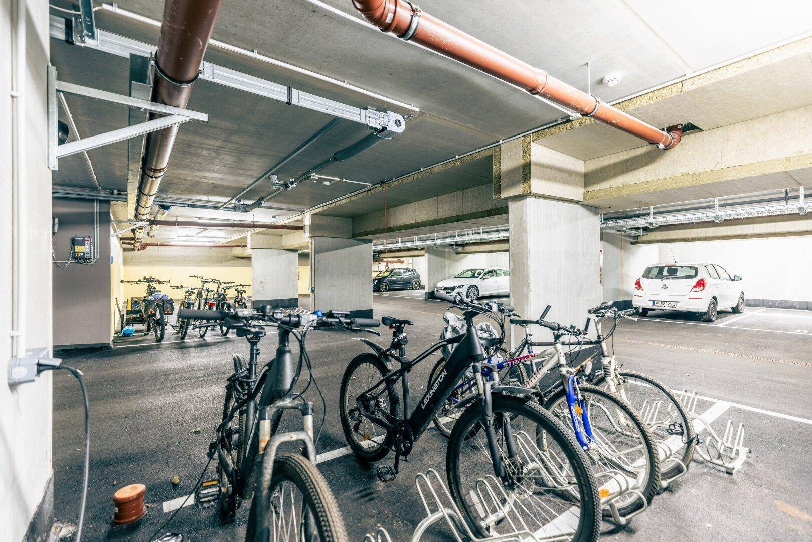 Tiefgarage mit Fahrradabstellplätzen und Parkmöglichkeiten für Autos, inklusive Ladestation.