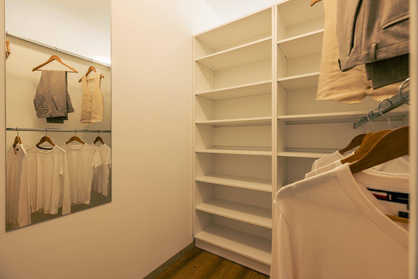 Geräumiger begehbarer Kleiderschrank mit Regalen und Kleiderstangen für optimale Organisation.