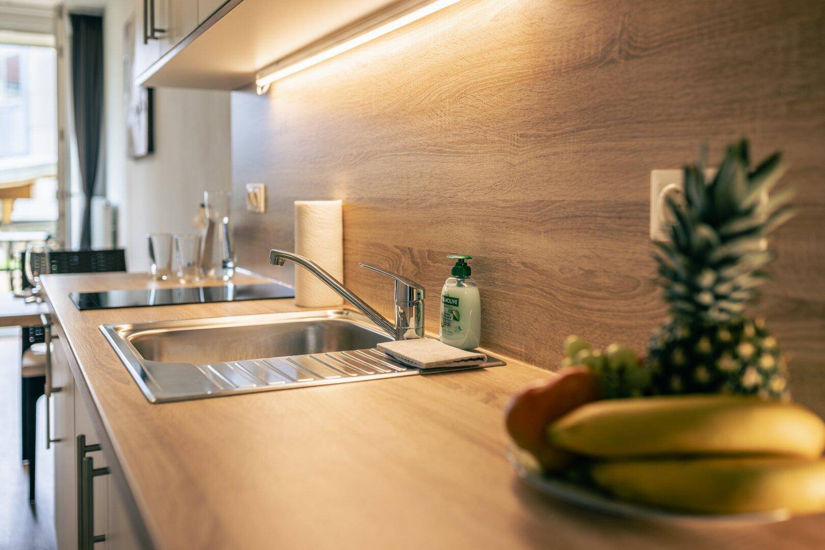 Funktionale Küchenzeile mit Spülbecken und Holz-Arbeitsplatte in hellem, modernem Design.