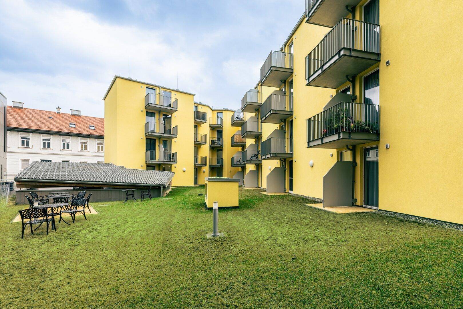 Grüner Innenhof mit Rasenfläche und Balkonen der modernen Wohnanlage.