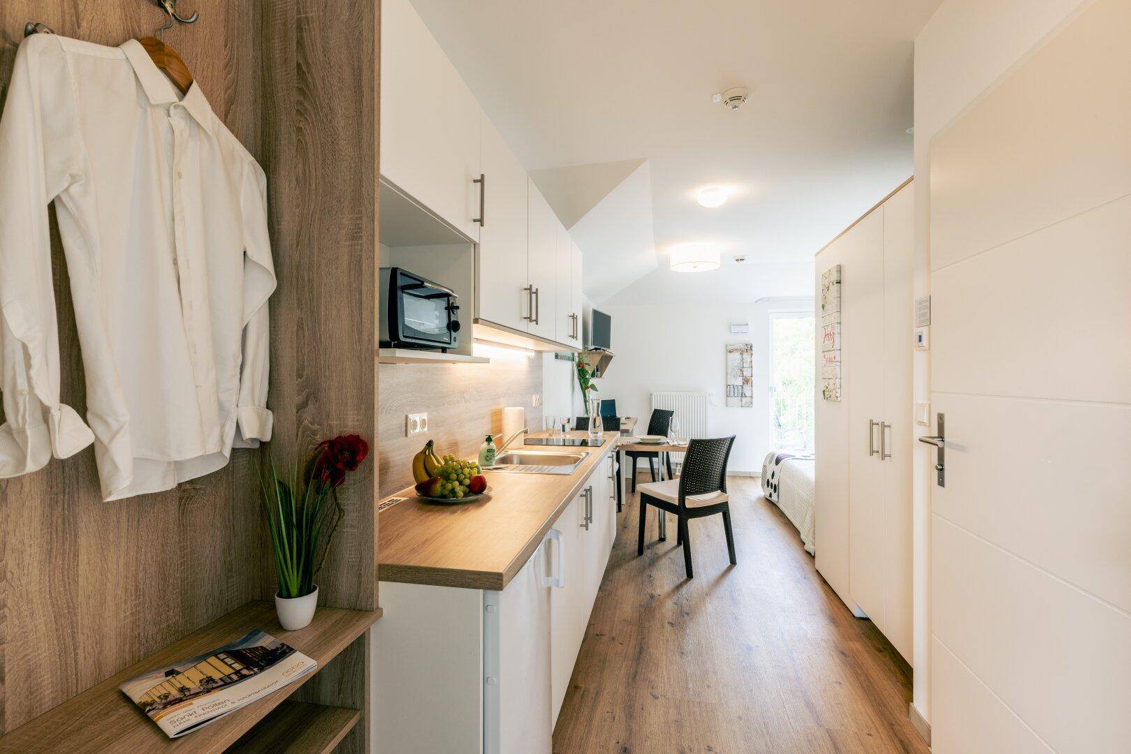 Moderner Eingangsbereich eines Studio-Apartments mit integrierter Küchenzeile und Essbereich.