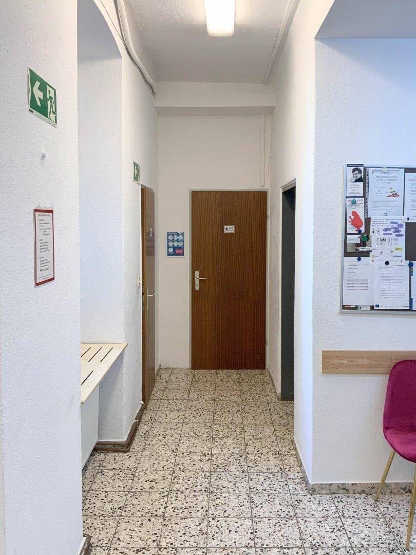 Schmaler Flur mit Fliesenboden und mehreren Türen, der zu verschiedenen Räumen führt.