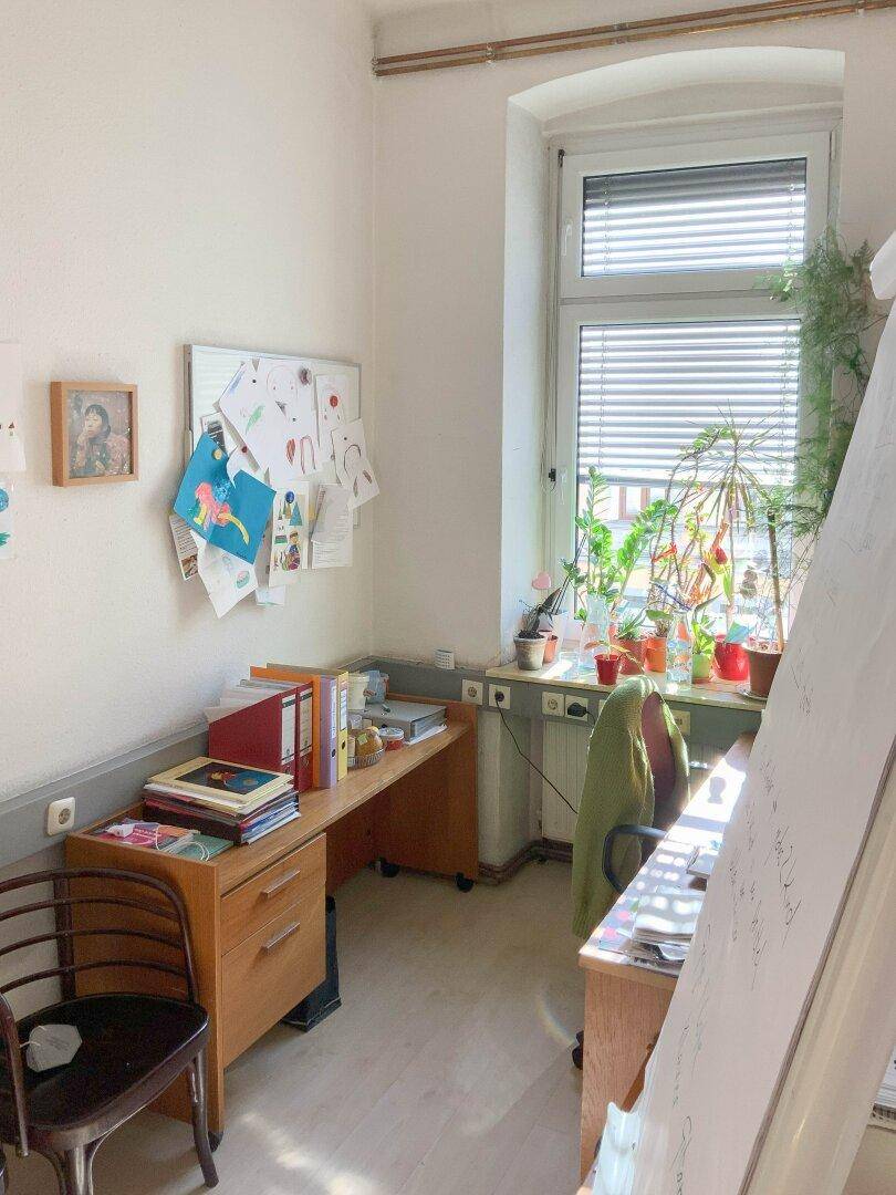 Kleines Büro mit Schreibtisch und vielen Pflanzen auf der Fensterbank, hell und gemütlich.