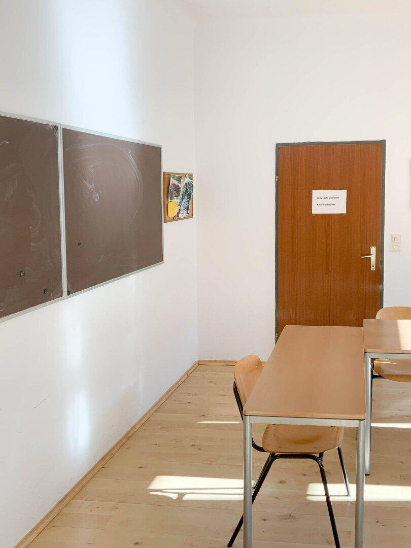 Schlichter Raum mit Holztür und Pinnwänden, geeignet für Notizen und Informationen.