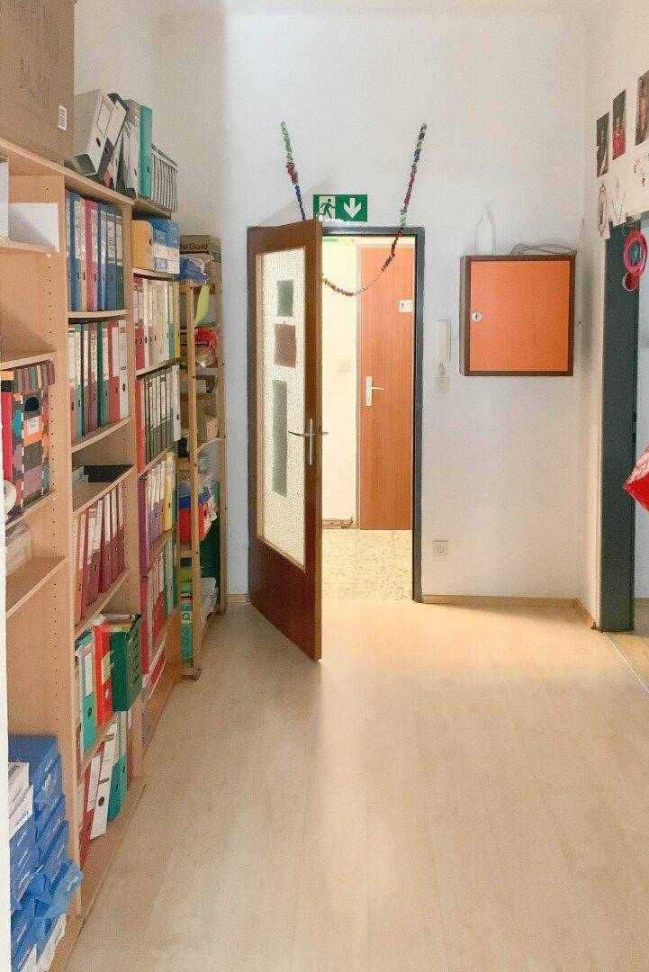 Langer Flur mit Bücherregalen voller Ordner und einer offenen Tür zu weiteren Räumen.
