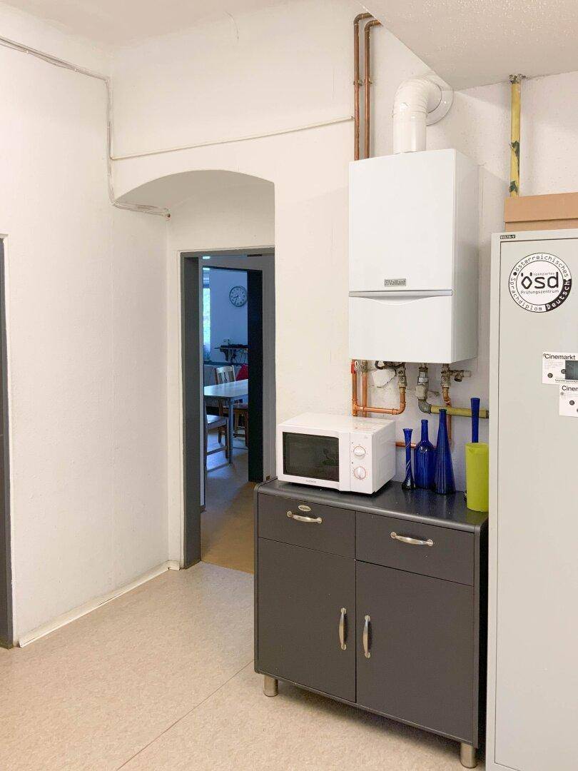 Kleiner Versorgungsraum mit Warmwasserbereiter, Mikrowelle und praktischen Schränken.