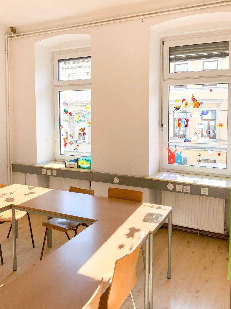 Große Fenster mit Fensterbänken in einem hellen Raum, geschmückt mit bunten Dekorationen.