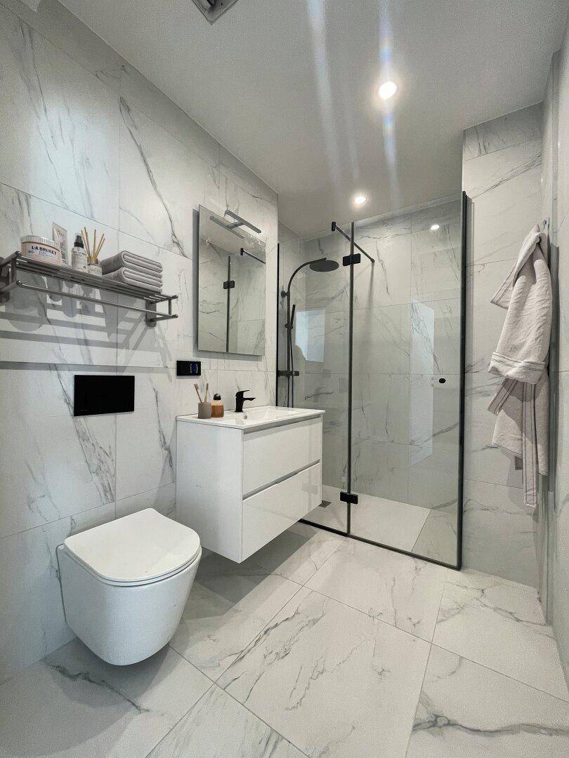 Modernes Badezimmer mit Marmorfliesen, begehbarer Dusche und wandhängendem WC in luxuriöser Ausführung.