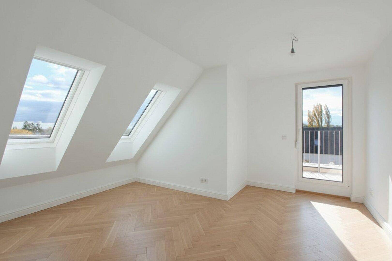 Lichtdurchflutetes Dachgeschosszimmer mit zwei Dachfenstern und Balkonzugang.