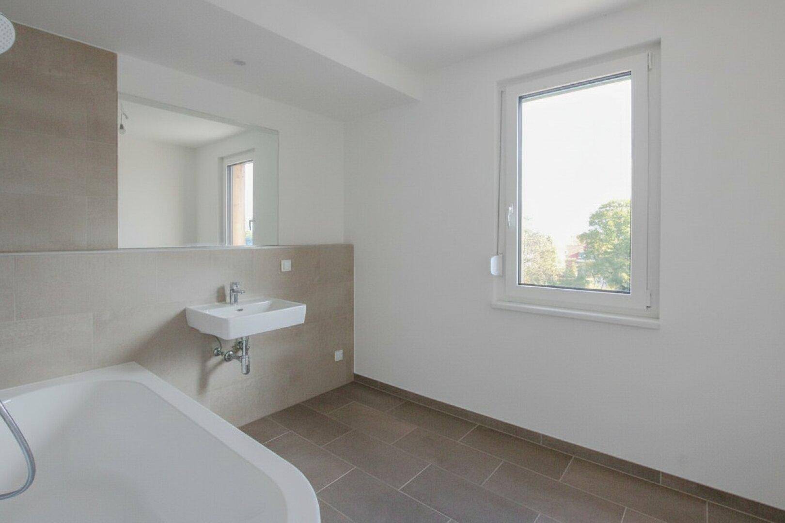 Helles Badezimmer mit Fenster, Einzelwaschbecken und modernen Fliesen.
