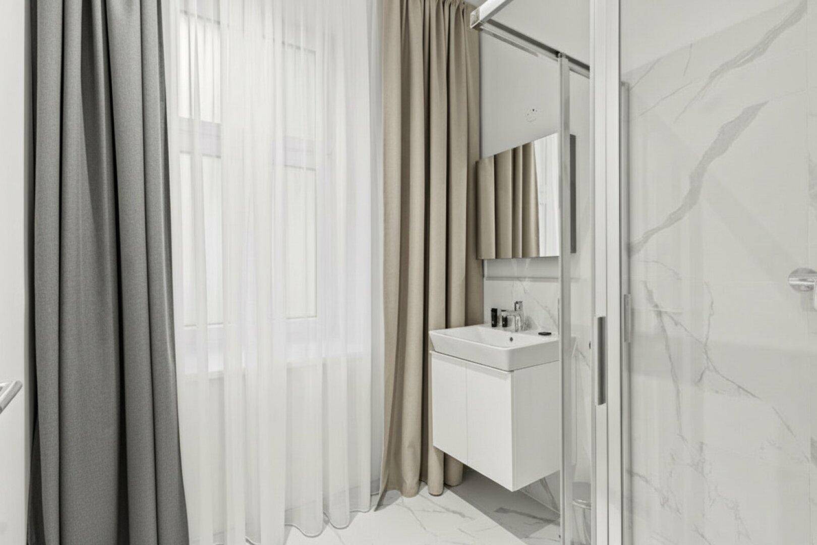 Modernes Badezimmer mit Duschkabine, schwebendem Waschbecken und großen Marmorfliesen.