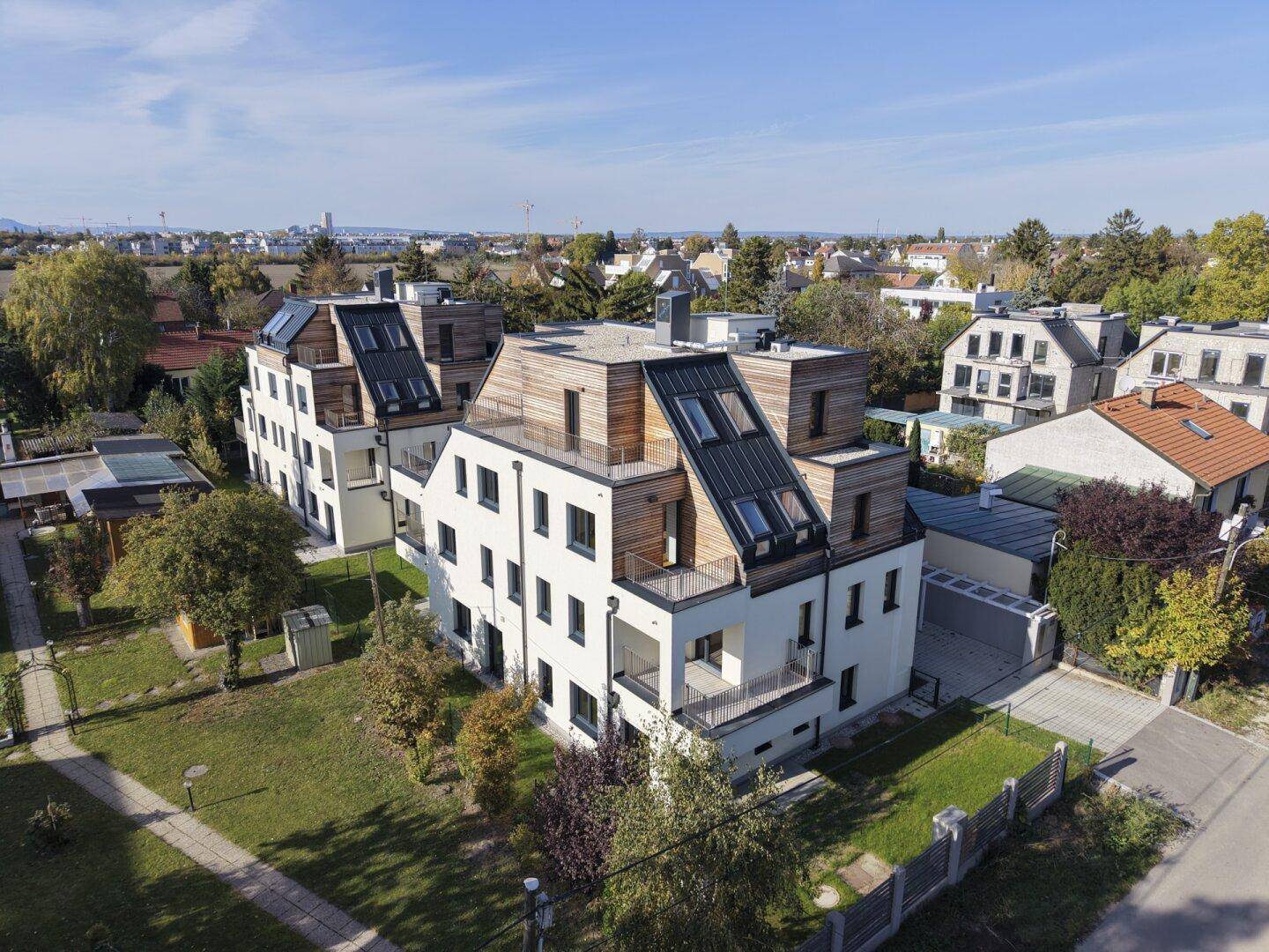 Luftaufnahme des modernen Wohnkomplexes mit Holzfassaden und grüner Umgebung.