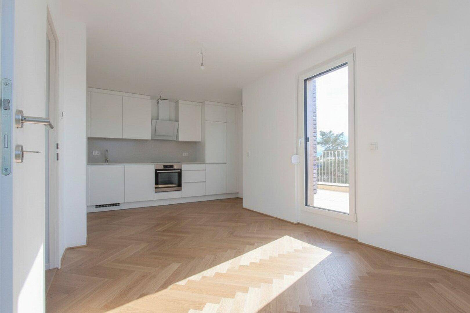 Moderne Einbauküche in Weiß mit Herd und Zugang zu einem sonnigen Balkon.