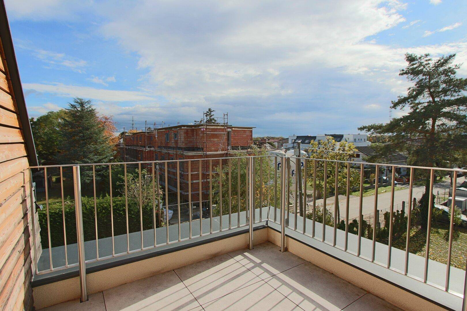 Geräumiger Balkon mit Fliesenboden und Blick auf die Umgebung und andere Gebäude.