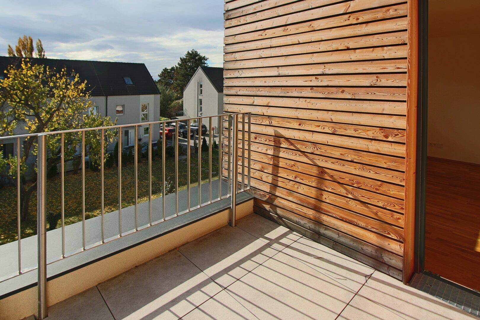 Balkon mit moderner Holzfassade und Ausblick auf die umliegenden Wohnhäuser.