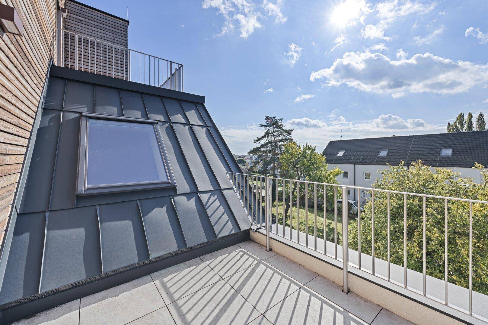 Sonniger Balkon mit Fliesenboden und Metallgeländer, bietet einen weiten Blick über die Umgebung.