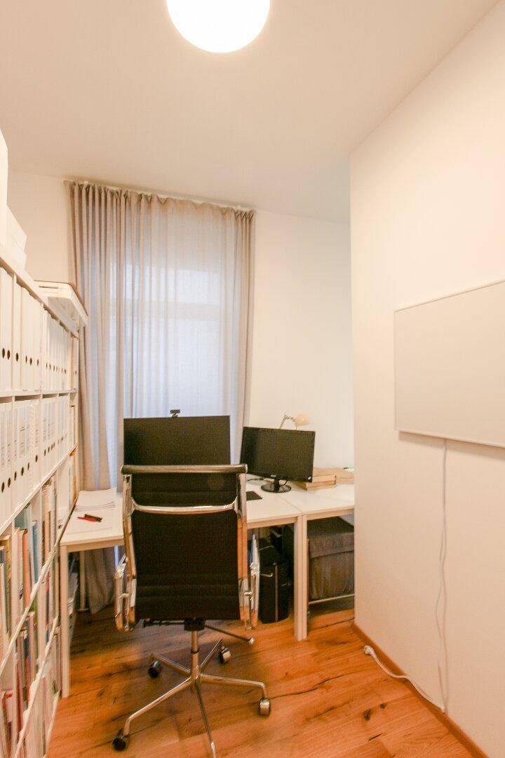 Funktionaler Arbeitsbereich mit Schreibtisch, Bürostuhl und Regalen, gut beleuchtet durch ein Fenster.