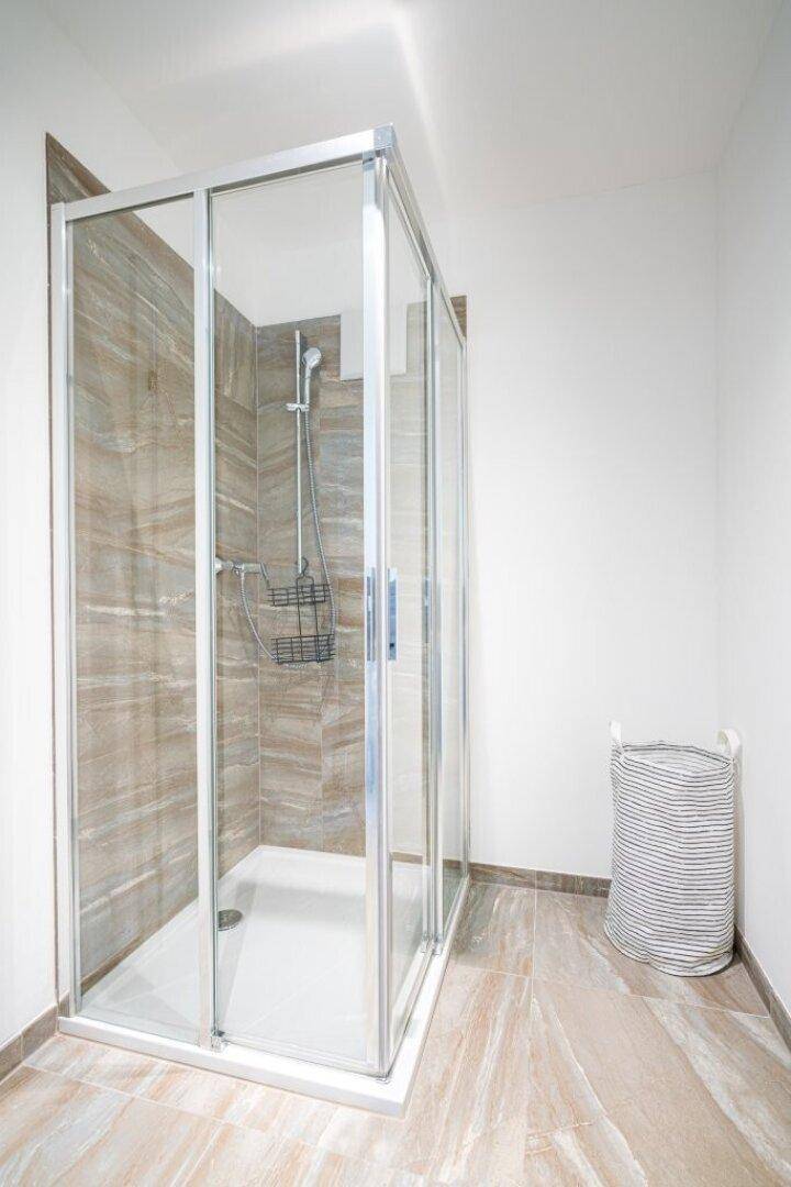 Moderne Duschkabine mit Glaswänden und eleganten Fliesen, bietet eine praktische Badlösung.