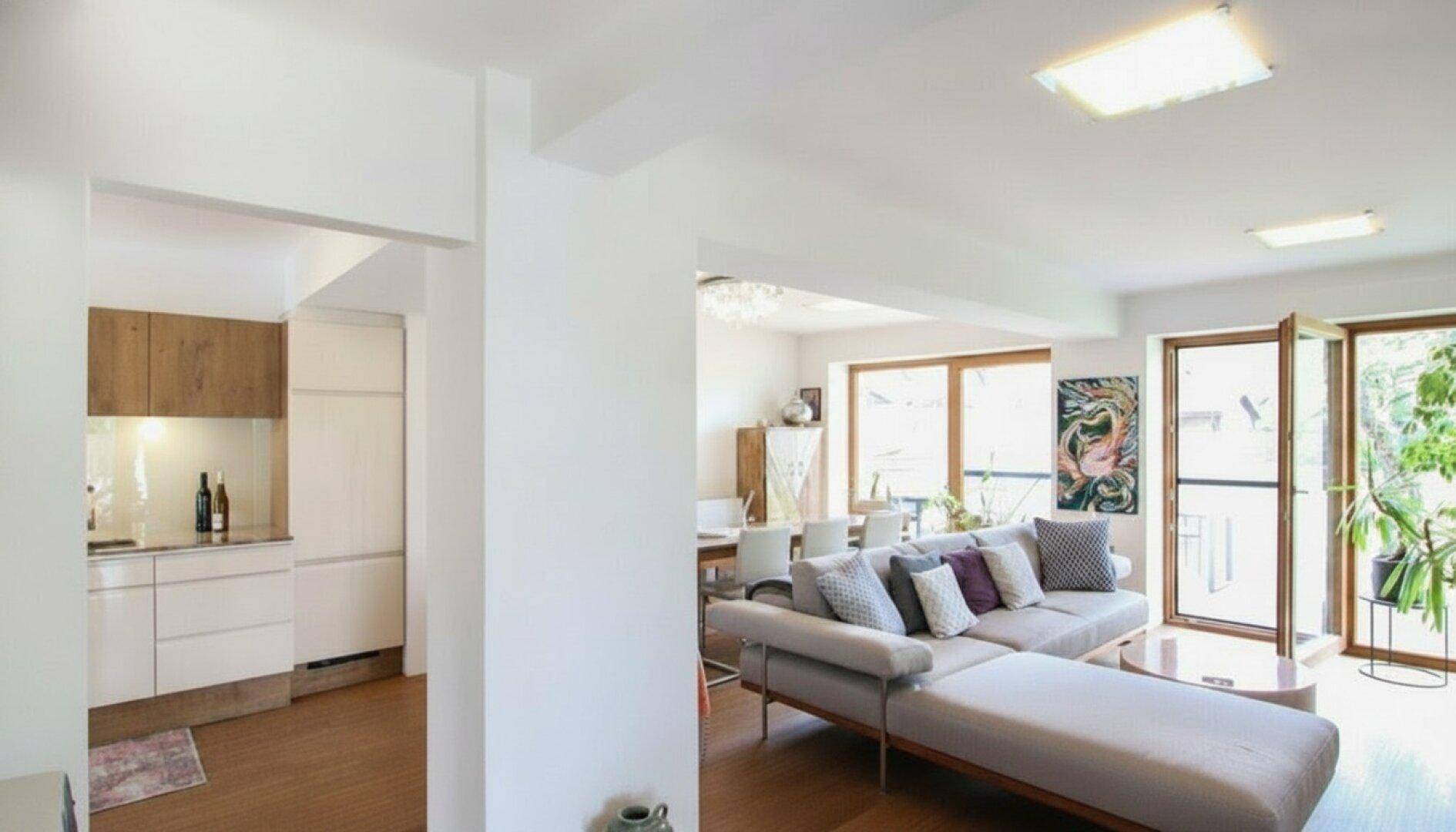 Offener Wohn- und Essbereich mit bequemer Couch, Holzboden und Zugang zur Küche.