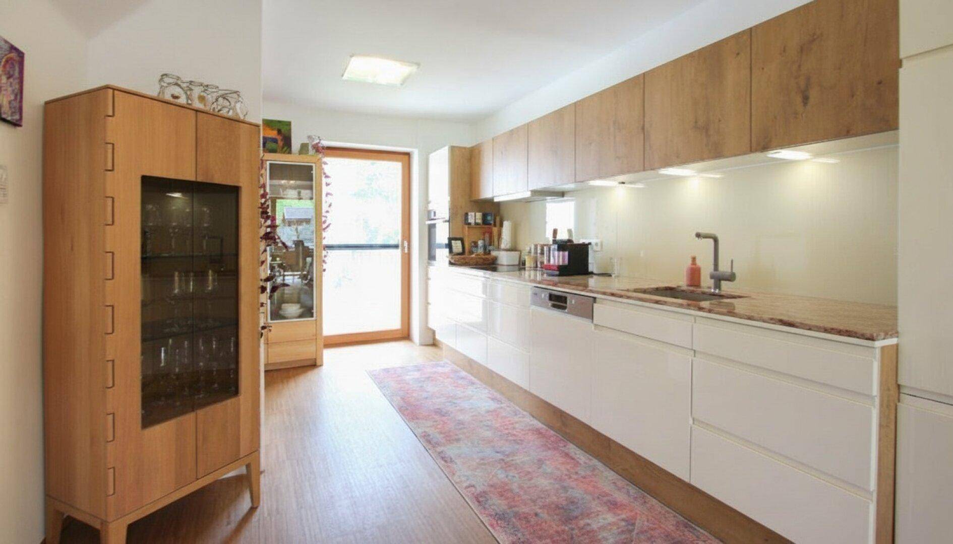 Moderne Küche mit Holz- und Hochglanzfronten, Granitarbeitsplatte und viel Stauraum.