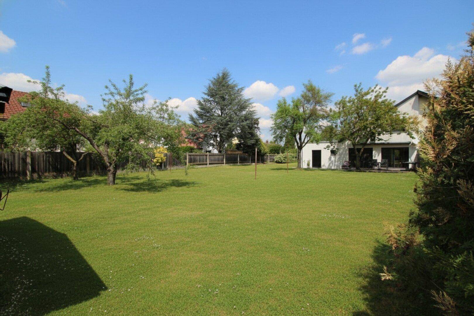 Großer, offener Gartenbereich mit viel Rasenfläche und Blick auf das moderne Gebäude.