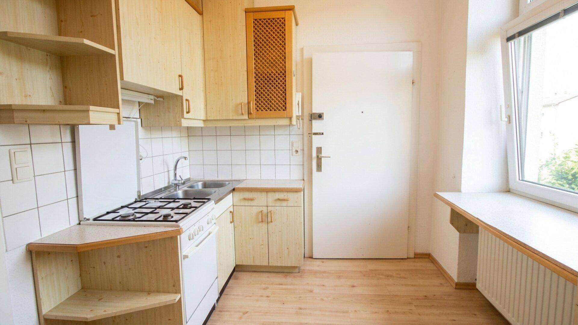Funktionale Küche mit Holzschränken, Gasherd und Fliesenboden, bereit zur Nutzung.