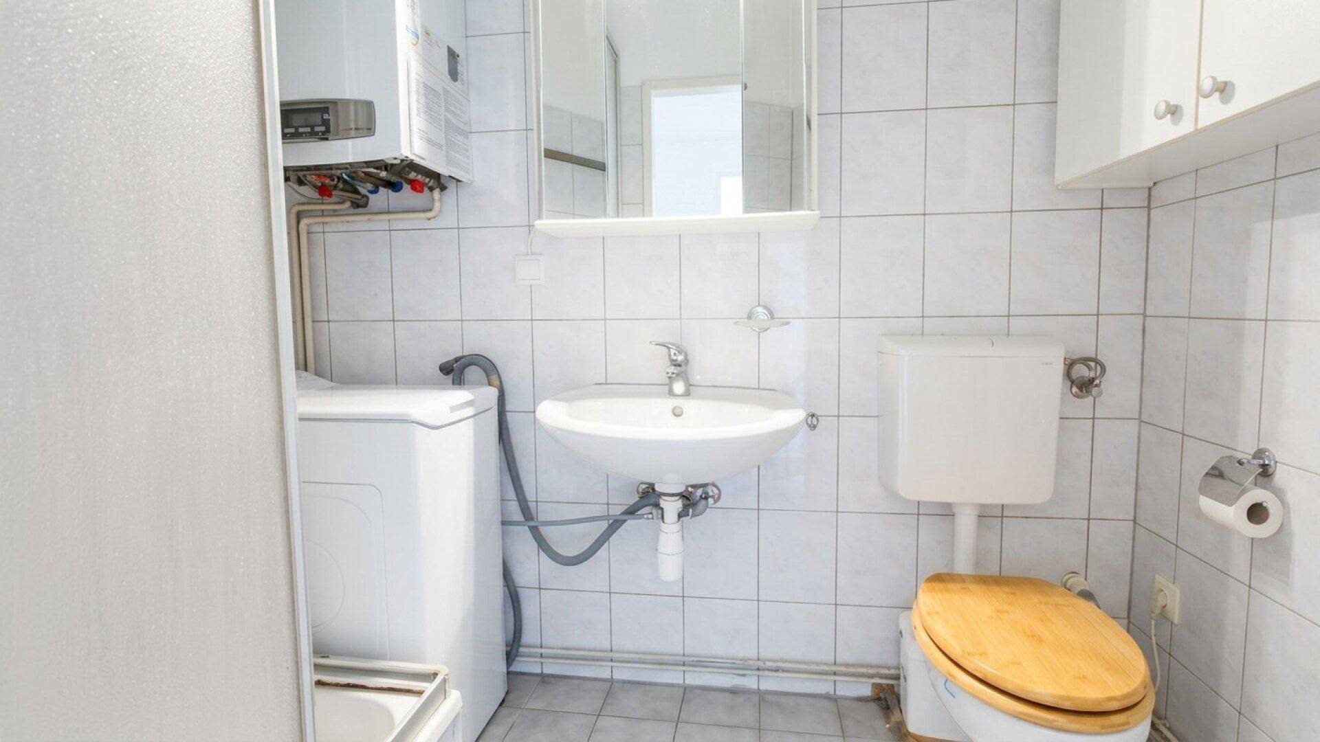 Kleines Badezimmer mit Dusche, WC und Waschbecken, ausgestattet mit Fliesen.