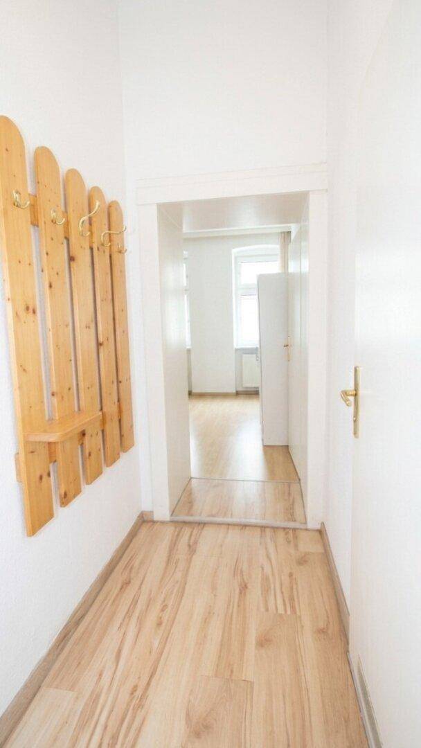 Heller Flur mit Garderobe aus Holz und Laminatboden, der zu weiteren Räumen führt.
