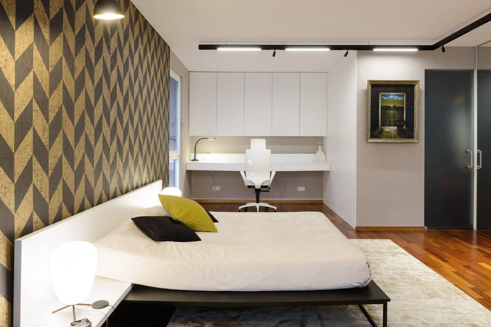 Schlafzimmer mit Holzboden, integriertem Schreibtisch und moderner Einrichtung.